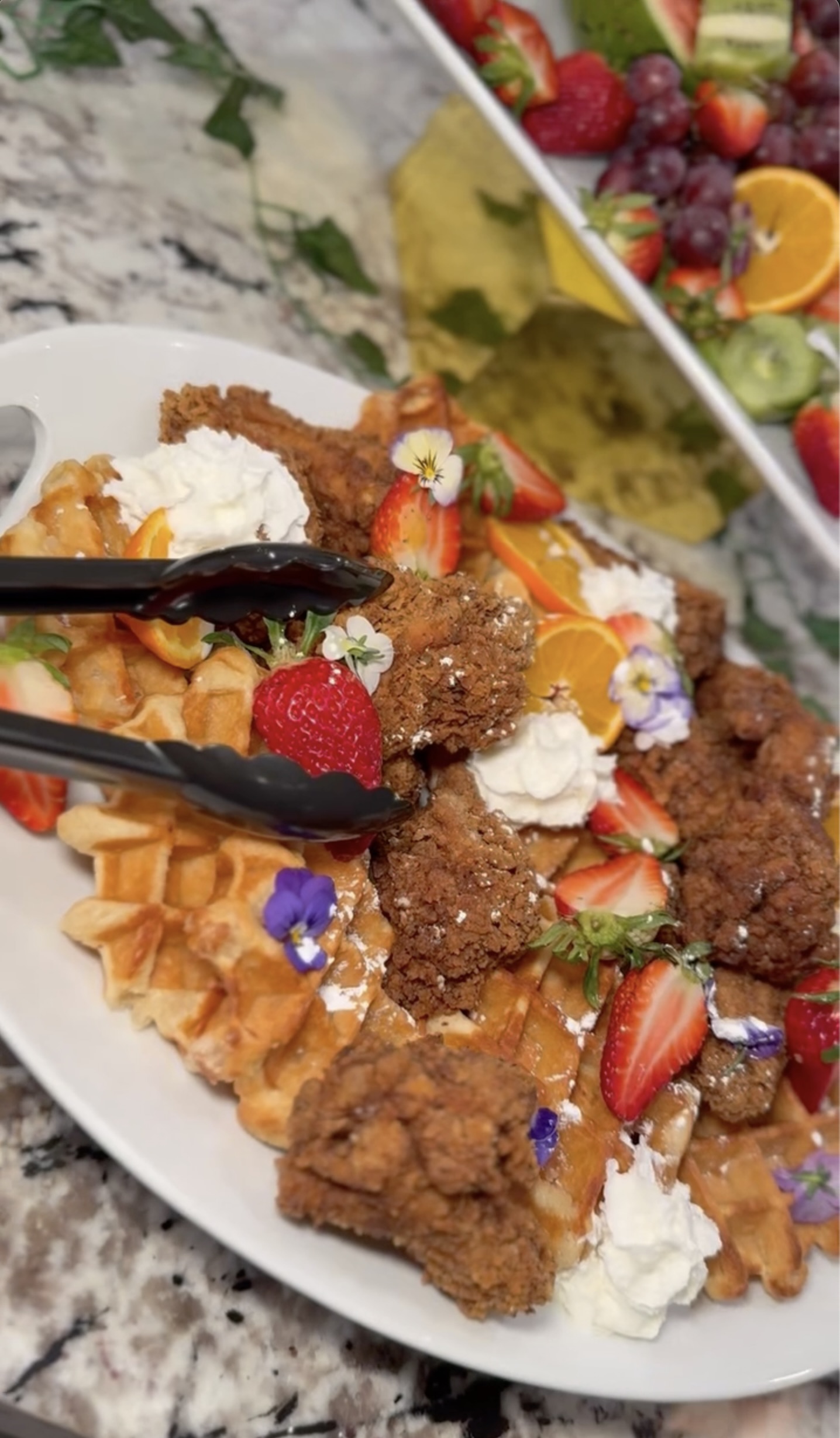 Southern-style fried chicken and waffles with strawberries and edible floral garnish